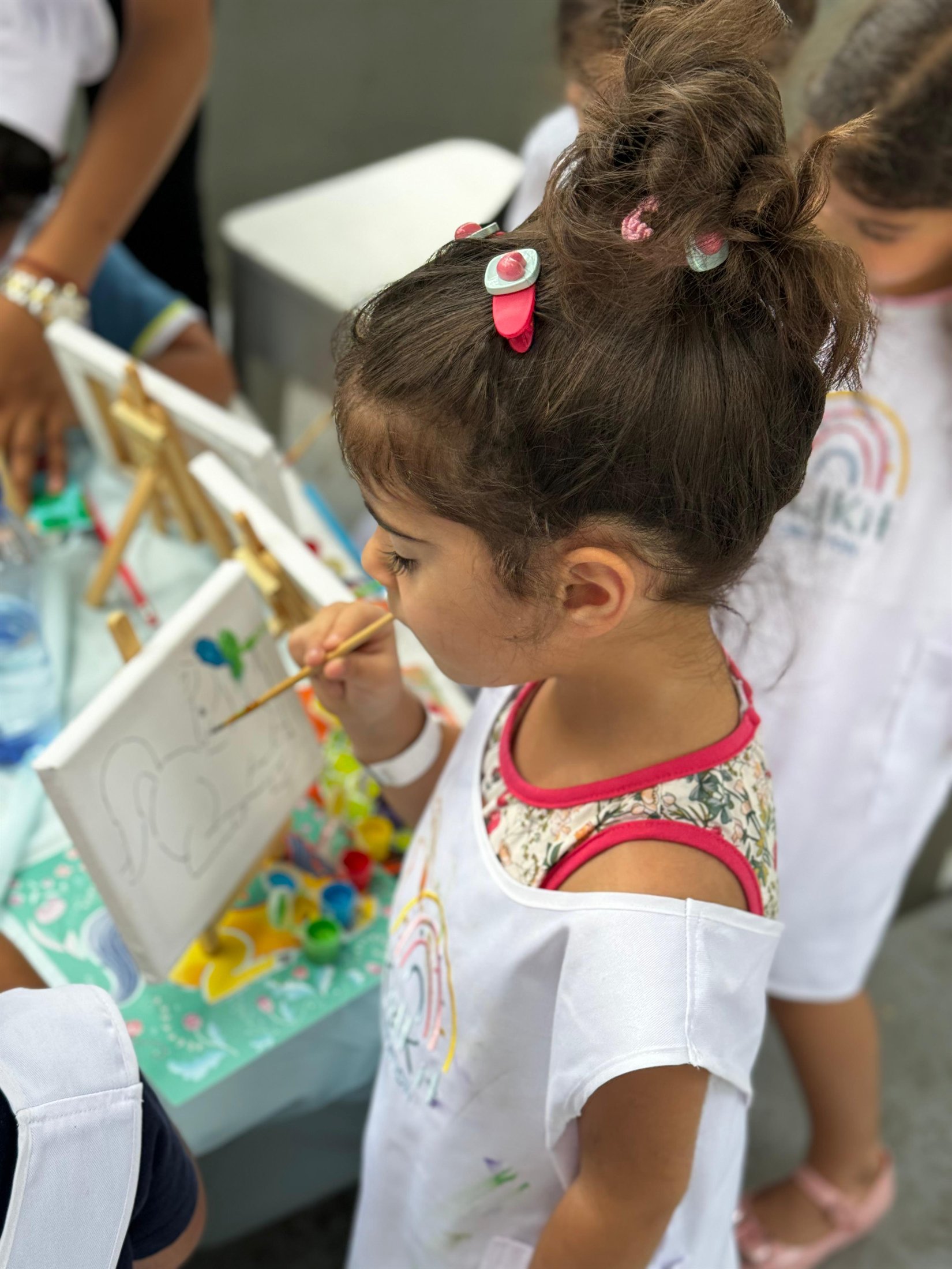 A little girl painting a canvas at a Kidkit creative workshop